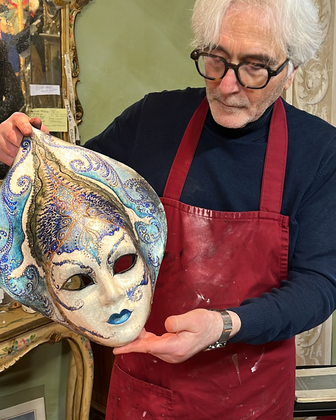 A skilled Venetian artisan holds a mask he made during a demonstration