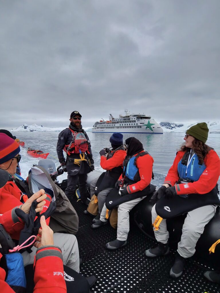 Guests sitting in a Zodiac after an expedition with an Aurora Expeditions ship in the background