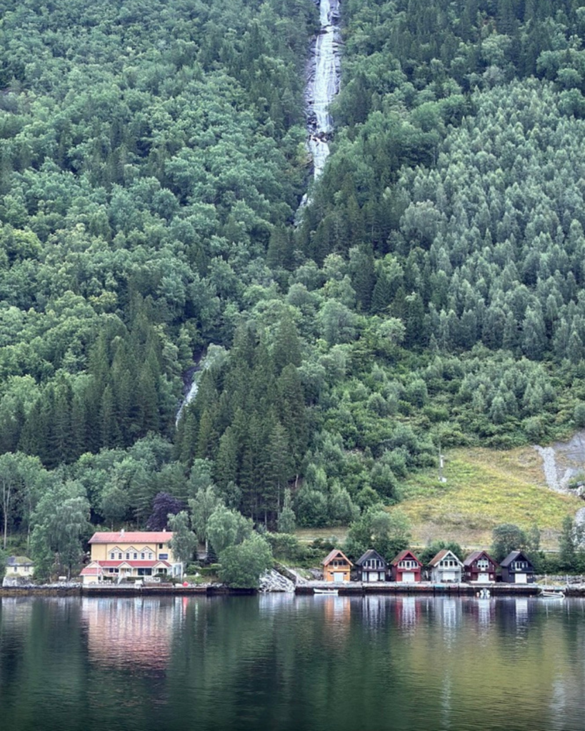 A waterfall and small homes in Vik, Norway as seen from Silver Spirit, a Silversea cruise ship
